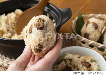 ハマグリの炊き込みご飯のおにぎりを手で持ち上げる 124733585