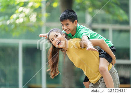 Joy and Laughter in Family Activities. A happy boy experiences the joy of being carried by his mom. Joy and Laughter in Family Activities. A happy boy experiences the joy of being carried by his mom. 124734354