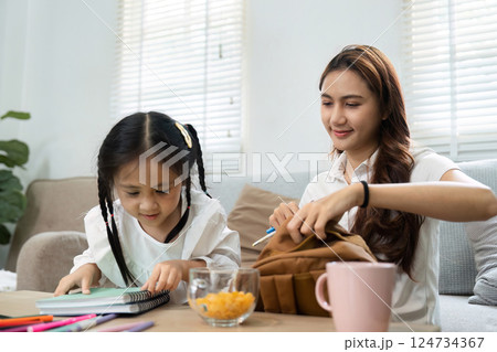 Learning and Family Bonding. A mother helps her daughter organize school supplies at home. 124734367