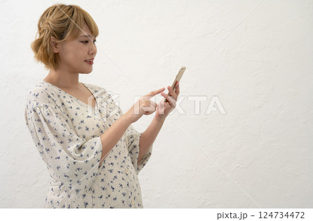 立ってスマホの操作をする妊婦さん 124734472