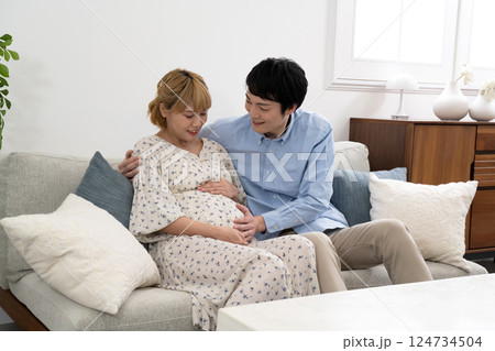 リビングでくつろぐ妊娠中の夫婦 リビングでくつろぐ妊娠中の夫婦 124734504