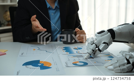 Business Meeting with Human and Robot Collaboration Analyzing Data Charts for Project Planning and Decision Making in Modern Office Environment. Noogenesis 124734758