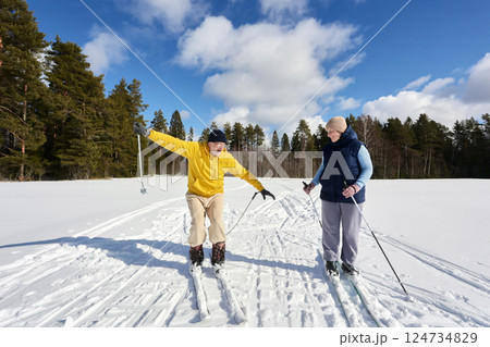 Mature couple enjoys winter day cross country skiing, their emotions ranging from shock to amusement amid snow covered field near forest, man has lost his balance. Mature couple enjoys winter day cross country skiing, their emotions ranging from shock to amusement amid snow covered field near forest, man has lost his balance. 124734829
