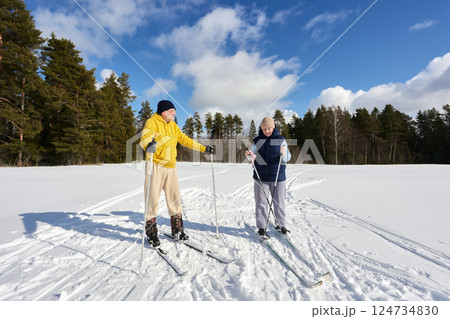 Taking short break from ski trip across snowy field, middle aged European couple enjoys sunny winter day. Taking short break from ski trip across snowy field, middle aged European couple enjoys sunny winter day. 124734830