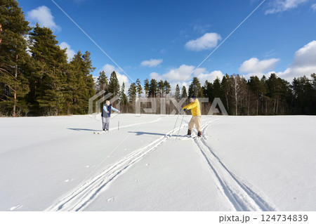 Couple in 50s pauses during cross country skiing, husband leans on poles, woman does too, both taking breather during winter excursion, snow all around. Couple in 50s pauses during cross country skiing, husband leans on poles, woman does too, both taking breather during winter excursion, snow all around. 124734839