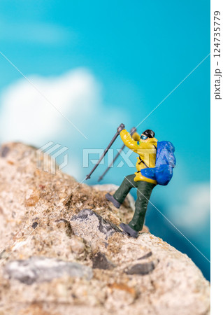 Miniature Climber Reaches Summit Against Majestic Mountain Backdrop 124735779