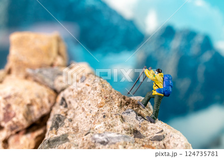 Miniature Climber Reaches Summit Against Majestic Mountain Backdrop Miniature Climber Reaches Summit Against Majestic Mountain Backdrop 124735781