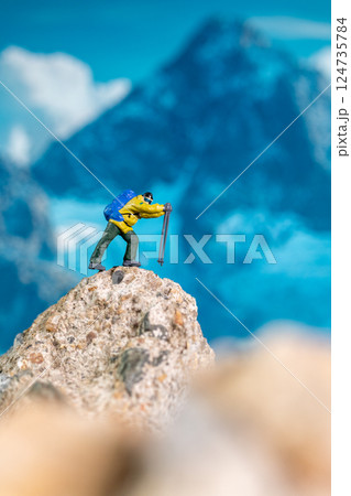 Miniature Climber Reaches Summit Against Majestic Mountain Backdrop Miniature Climber Reaches Summit Against Majestic Mountain Backdrop 124735784
