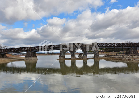 澄んだ池の水に浮かぶ石造りの眼鏡橋 124736081