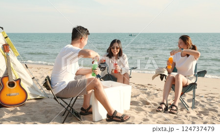 Happy friends with drinks in camp and laughing together in holidays on sand beach near camping tent vacation time at sunset, Young Asian group woman and man in summer travel outdoor 124737479