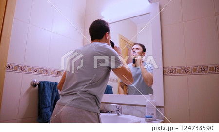 Man removing nose hair with electric trimmer in bathroom mirror Man removing nose hair with electric trimmer in bathroom mirror 124738590