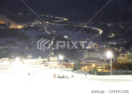 ナイター照明で白く反射するゲレンデと自動車道路の車のライト 124741180