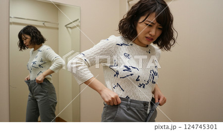 試着室でサイズの合わないパンツに苦戦する日本人女性 試着室でサイズの合わないパンツに苦戦する日本人女性 124745301