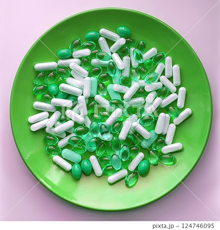 Medical pills and herb capsules on green plate 124746095