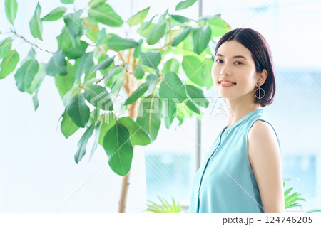 部屋でスマホを操作する夏服の若い女性 124746205