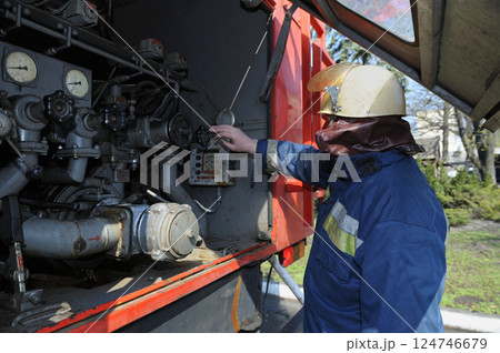 Fireman switching the water pump engine on control panel 124746679