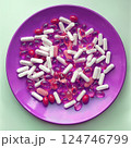 Medicine pills and herbal capsules on a pink plate  124746799