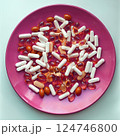 Medicine pills and herbal capsules on red plate 124746800