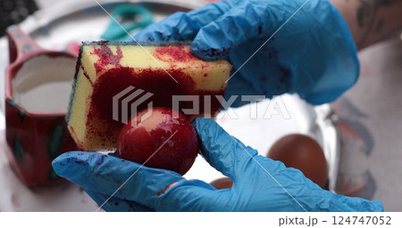 Red Easter egg painting featuring vibrant colors for decorating and coloring eggs during festive celebrations Red Easter egg painting featuring vibrant colors for decorating and coloring eggs during festive celebrations 124747052