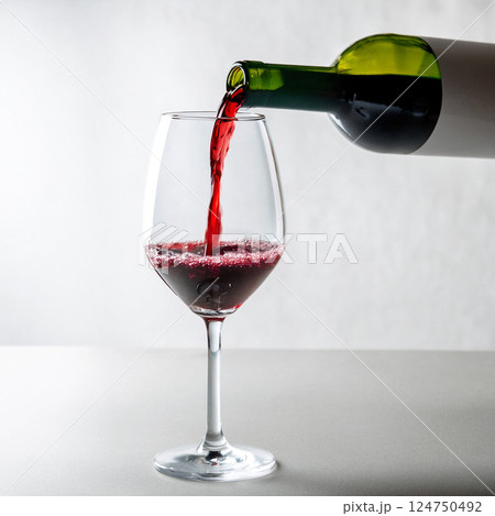 緑の瓶からワイングラスに赤ワインを注ぐ瞬間　明るく白い背景 124750492