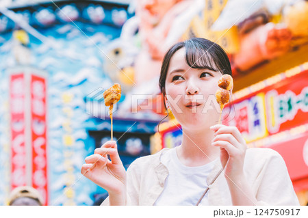大阪の新世界で名物串カツを食べる若い女性 124750917