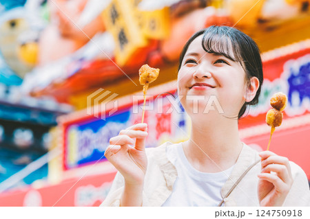 大阪の新世界で名物串カツを食べる若い女性 大阪の新世界で名物串カツを食べる若い女性 124750918