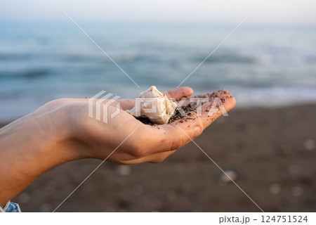 Young woman holding seashell against sea 124751524