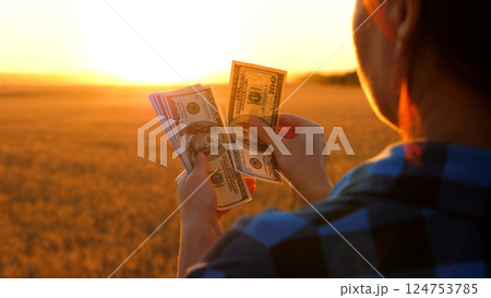 Farmer holding money in hands, counting profit from selling crops. Agriculture income. Farming economy, agricultural profitability, agribusiness growth. 124753785