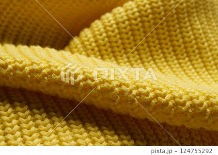 Knitted clothes. Waves of yellow fabric with a knitting pattern. Textiles. Banner for advertising goods for creativity. 124755292