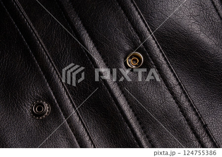 Close up of black leather with metal button. Textiles. Close up of black leather with metal button. Textiles. 124755386