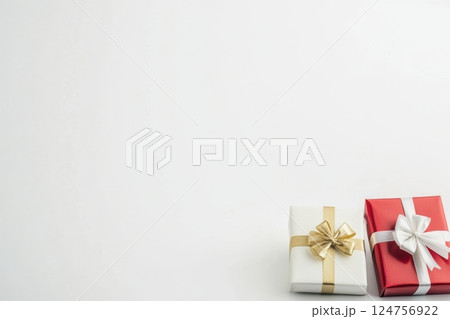 elegant holiday gift set with three beautifully wrapped presents in red and gold, adorned with luxurious ribbons and carefully tied bows, rich textured paper, festive celebration mood 124756922