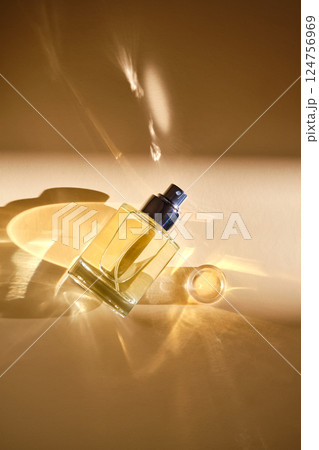 Perfume on a beige background in the rays of bright sun with beautiful highlights. 124756969