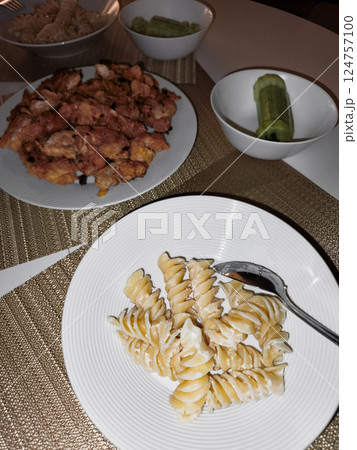 Spring dinner table setting with pasta, fried chicken nuggets, cucumber dinner 124757100