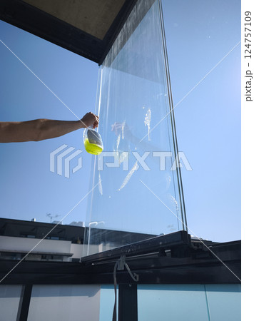 Window cleaner cleaning glass balcony with detergent and sponge in spring time 124757109