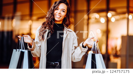 Beauty woman with shopping bags walks through the sunny streets of Europe. Consumerism, shopping Beauty woman with shopping bags walks through the sunny streets of Europe. Consumerism, shopping 124757175