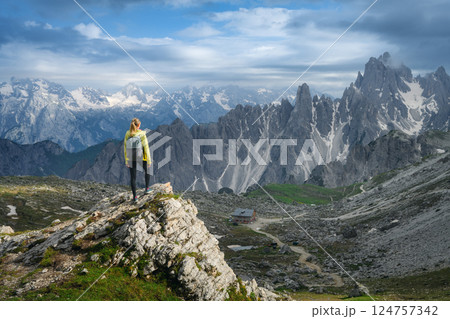 Young woman with backpack on a rock in majestic mountain valley Young woman with backpack on a rock in majestic mountain valley 124757342