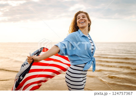 Young woman with American flag on beach. Patriotic holiday. Independence Day concept 124757367