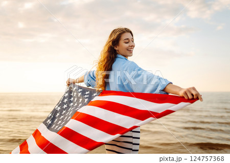 Young woman with American flag on beach. Patriotic holiday. Independence Day concept Young woman with American flag on beach. Patriotic holiday. Independence Day concept 124757368