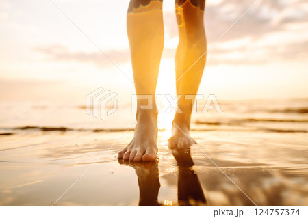 Woman leg close up walking on sand relaxing in beach at sunset. Sexy lean and tanned legs. 124757374