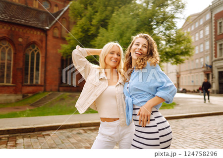 Two beautiful women are walking down the street. Fun and walking concept. Active lifestyle. 124758296