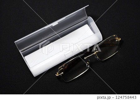 Corrective glasses with a case on a black background. 124758443