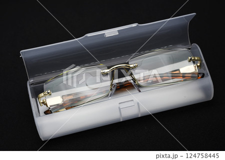 Corrective glasses with a case on a black background. 124758445