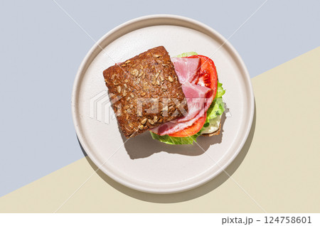 Toast sandwich made of grain bread with prosciutto, tomatoes, lettuce and sauce  124758601