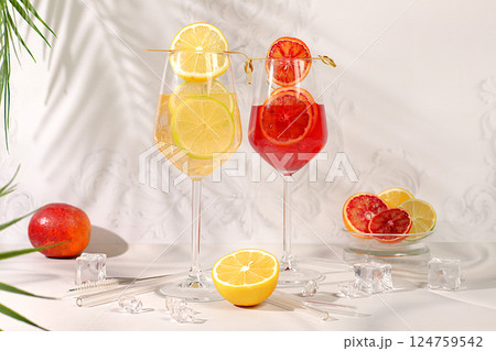 Flyer with glasses of alcoholic drinks and tropical fruits. Two royal cocktails of blood orange and lemon, ice cubes, rum and tequila. Concept of a summer party and rest in a restaurant. Flyer with glasses of alcoholic drinks and tropical fruits. Two royal cocktails of blood orange and lemon, ice cubes, rum and tequila. Concept of a summer party and rest in a restaurant. 124759542