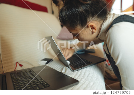 A Focused Woman Engaged in Work on Laptops in Her Cozy and Inviting Workspace Area 124759703