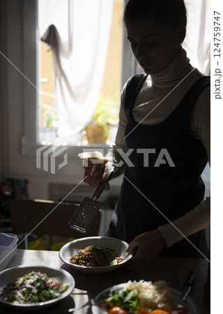 A woman is busily preparing a delicious and nutritious meal in her sunlit kitchen space 124759747