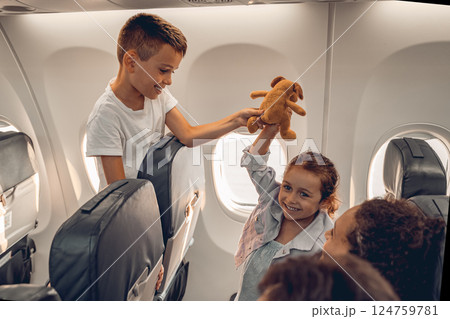 Children happily play with a stuffed animal on an airplane, making joyful memories Children happily play with a stuffed animal on an airplane, making joyful memories 124759781