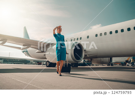 The Airline Stewardess Welcomes Passengers with a Warm Smile at the Airport Terminal 124759793