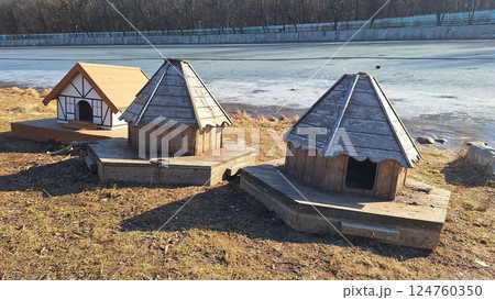 Wooden duck houses by frozen lake in winter sunlight 124760350