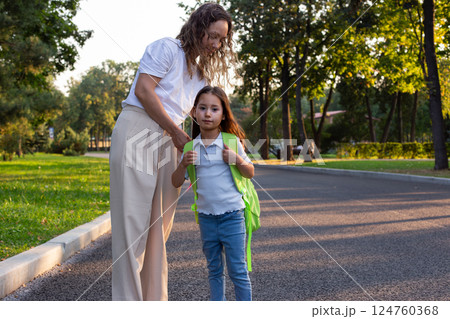 Mother and daughter walking to school on a sunny morning Mother and daughter walking to school on a sunny morning 124760368